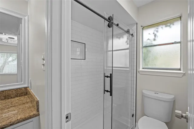 a bathroom with a granite countertop toilet a sink and shower