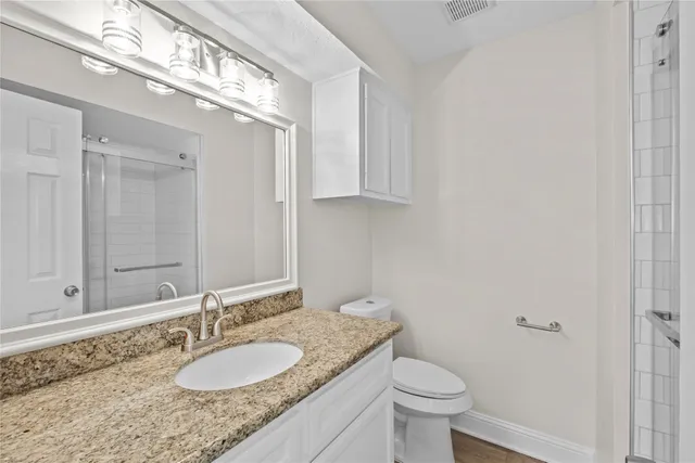 a bathroom with a granite countertop sink a toilet and a mirror