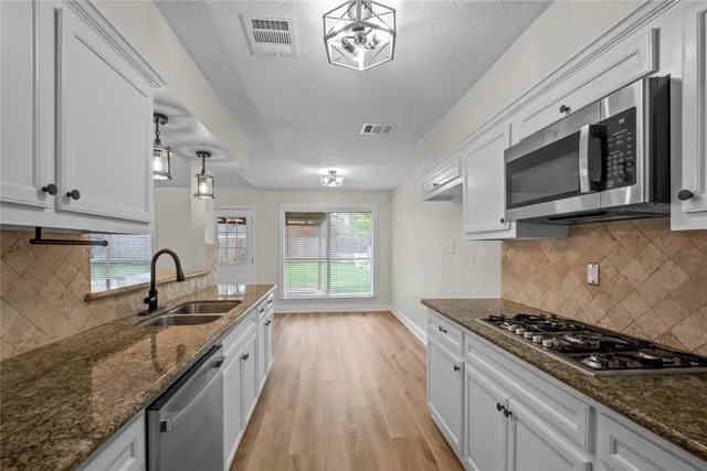 a kitchen with granite countertop a sink a stove and cabinets