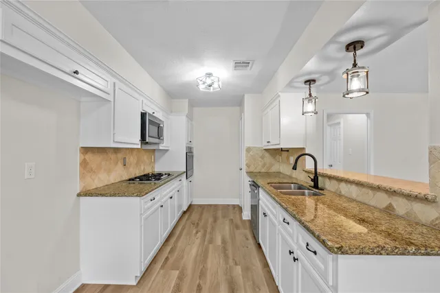 a kitchen with granite countertop a sink a counter space appliances and cabinets