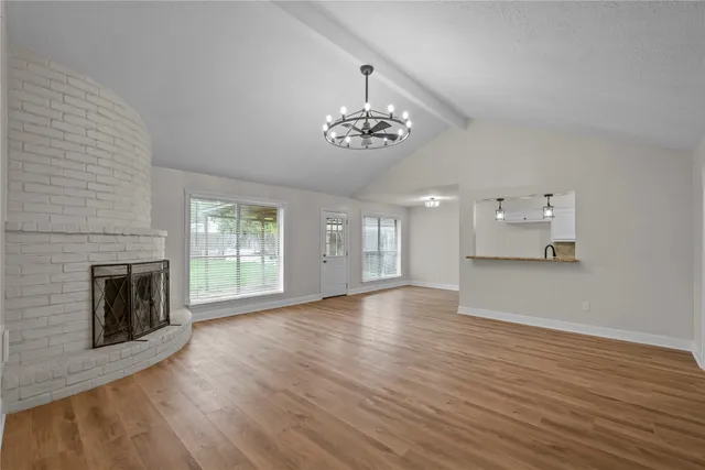 an empty room with wooden floor fireplace and windows
