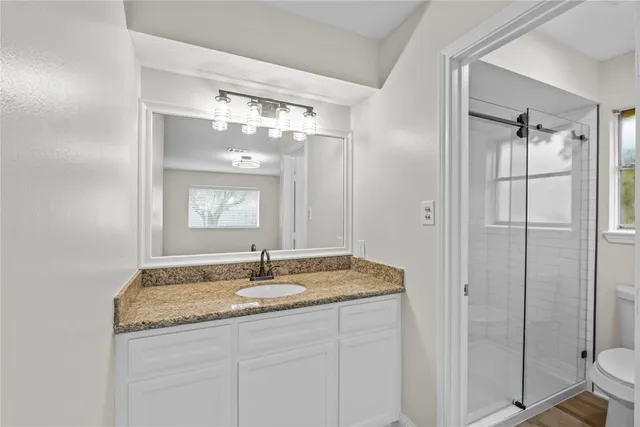 a bathroom with a granite countertop sink a mirror and a shower