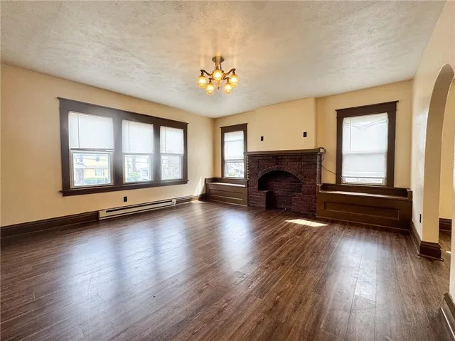 an empty room with fireplace wooden floor and windows
