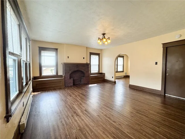 an empty room with wooden floor and fireplace