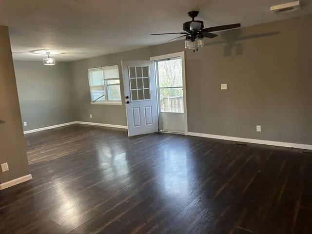 a view of an empty room with a window and wooden floor