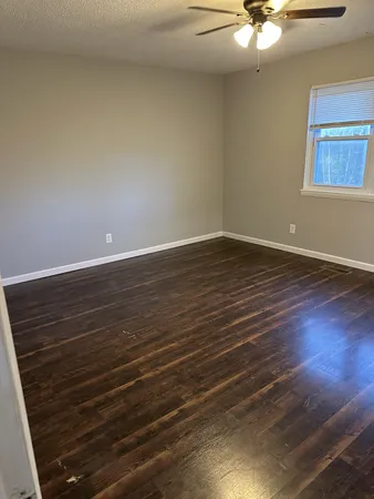 a view of an empty room with wooden floor and a chandelier
