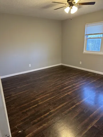 a view of an empty room with wooden floor and a chandelier