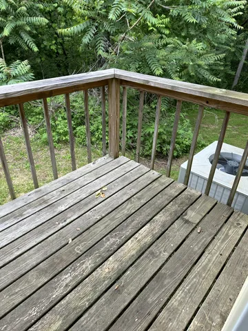a view of roof deck with wooden floor and fence next to a yard