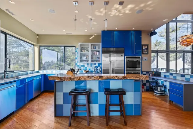 a kitchen with granite countertop a dining table chairs wooden floor and appliances