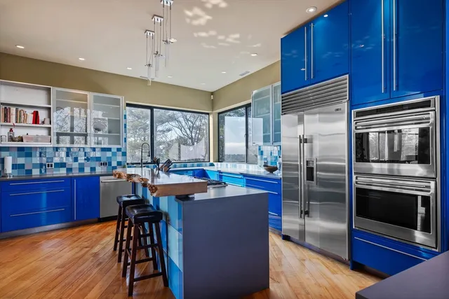 a kitchen with stainless steel appliances kitchen island granite countertop a table chairs and a refrigerator