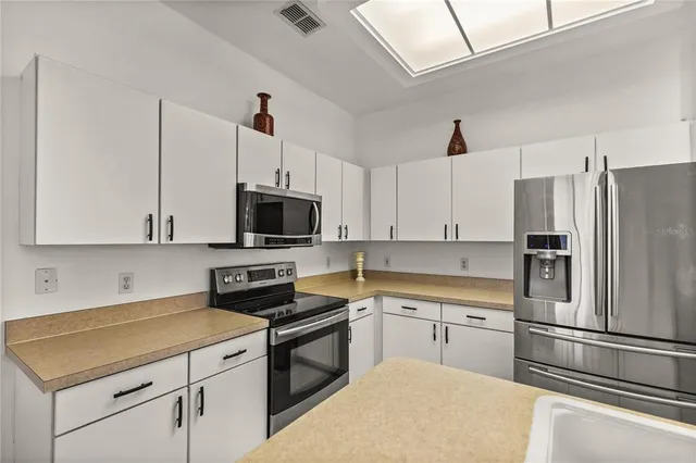 a kitchen with cabinets stainless steel appliances and wooden floor