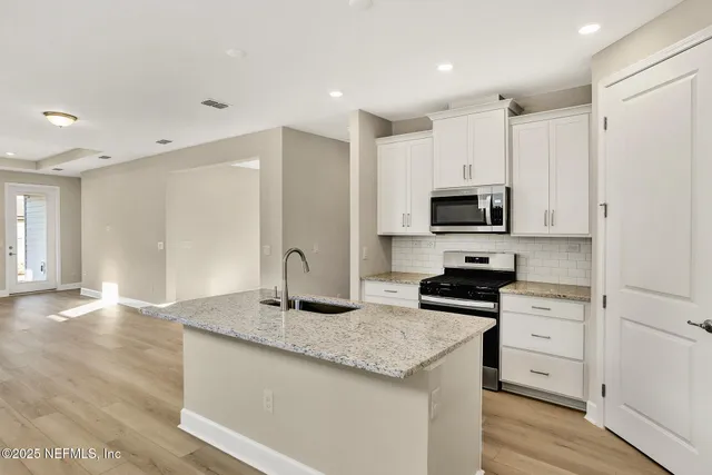 a kitchen with granite countertop a sink a stove a microwave a counter space and cabinets