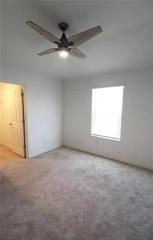 an empty room with a window and a fan