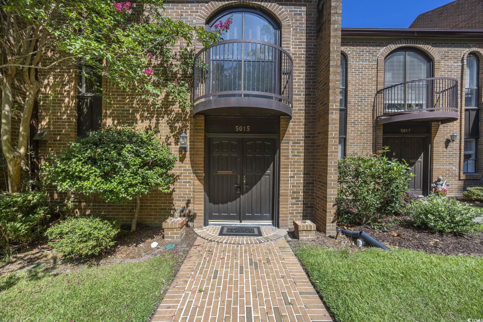 View of exterior entry featuring brick siding and a balcony