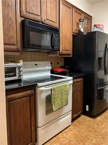 a kitchen with granite countertop a refrigerator stove and microwave