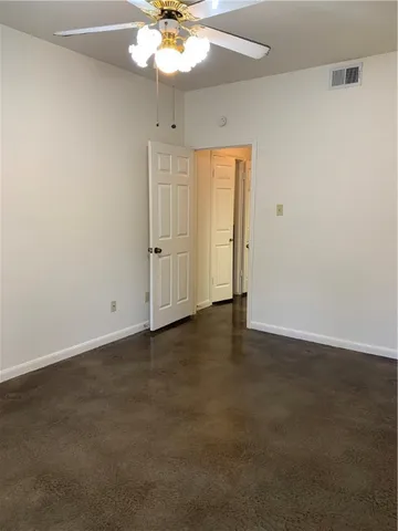 an empty room with a chandelier fan and wooden floor