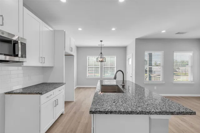 a kitchen with kitchen island granite countertop a counter top space cabinets stainless steel appliances and a sink