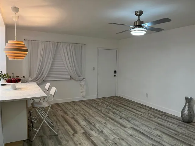 a room with a chandelier fan and wooden floor
