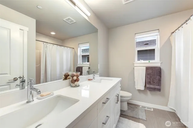 a bathroom with a double vanity sink toilet and mirror