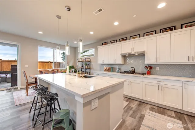 a large white kitchen with wooden floor