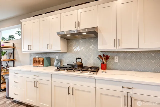a kitchen with stainless steel appliances granite countertop a sink a stove and white cabinets