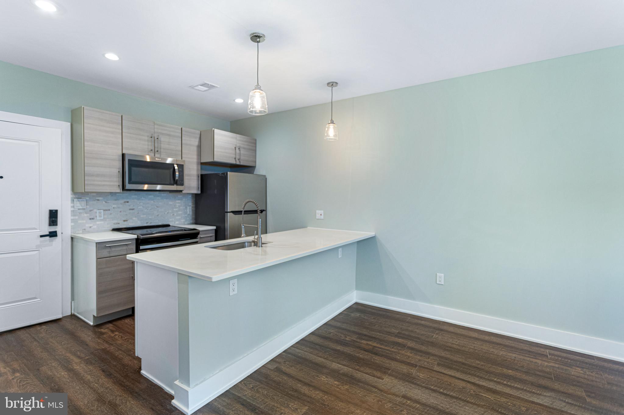 1219 K Street Northeast, Unit 203 Washington, DC 20002 - Photo 3 of 10 a kitchen with a sink a counter top space stainless steel appliances and cabinets