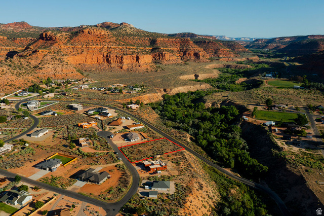 50 Dry Gulch Road, Unit 50 Kanab, UT 84741 - Photo 17 of 20 Expansive lot bordered by a paved road, featuring a backdrop of natural rock formations and a verdant valley