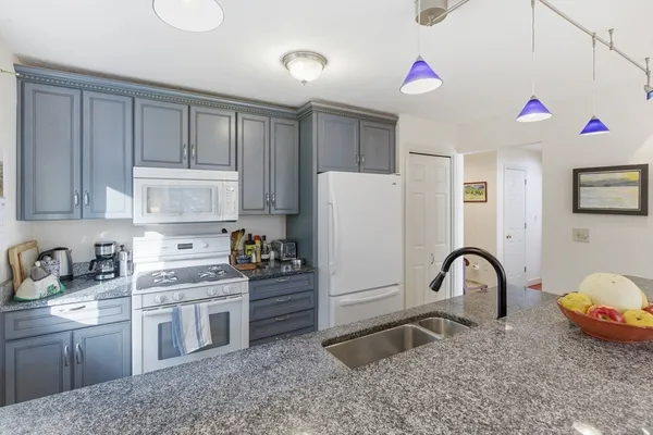 a kitchen with a sink white cabinets and appliances