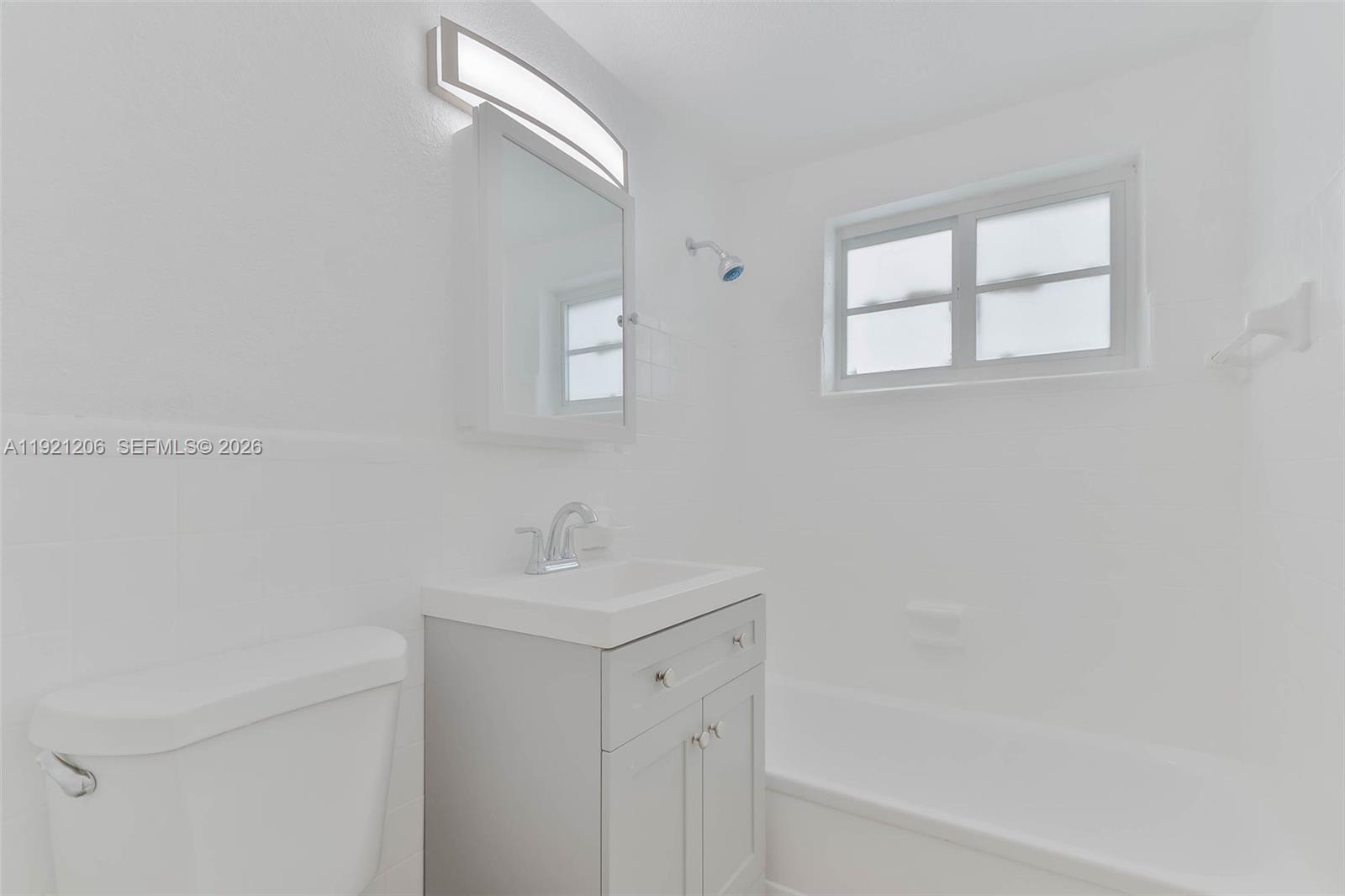 6921 Rue Vendome, Unit 1 Miami Beach, FL 33141 - Photo 10 of 27 a bathroom with a sink a mirror and a window