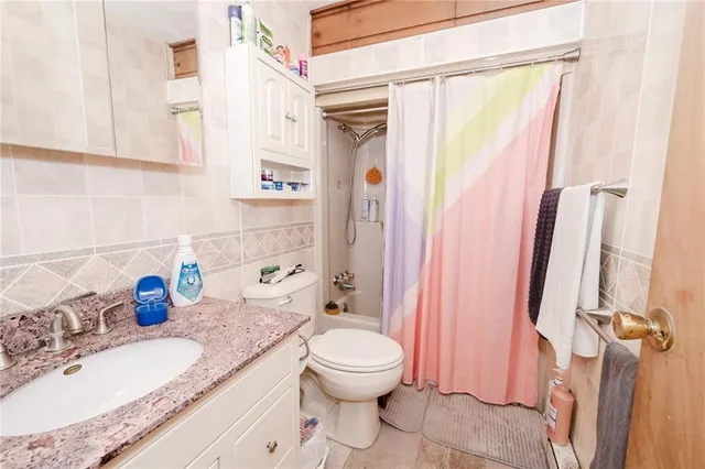 a bathroom with a granite countertop sink a toilet and a shower curtain