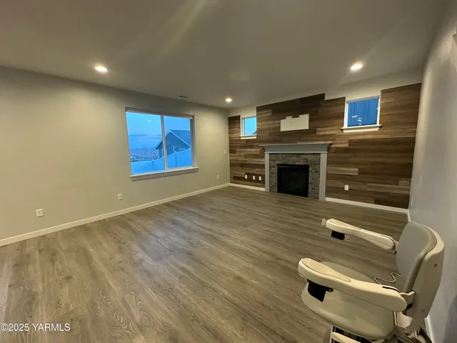 an empty room with wooden floor fridge and windows