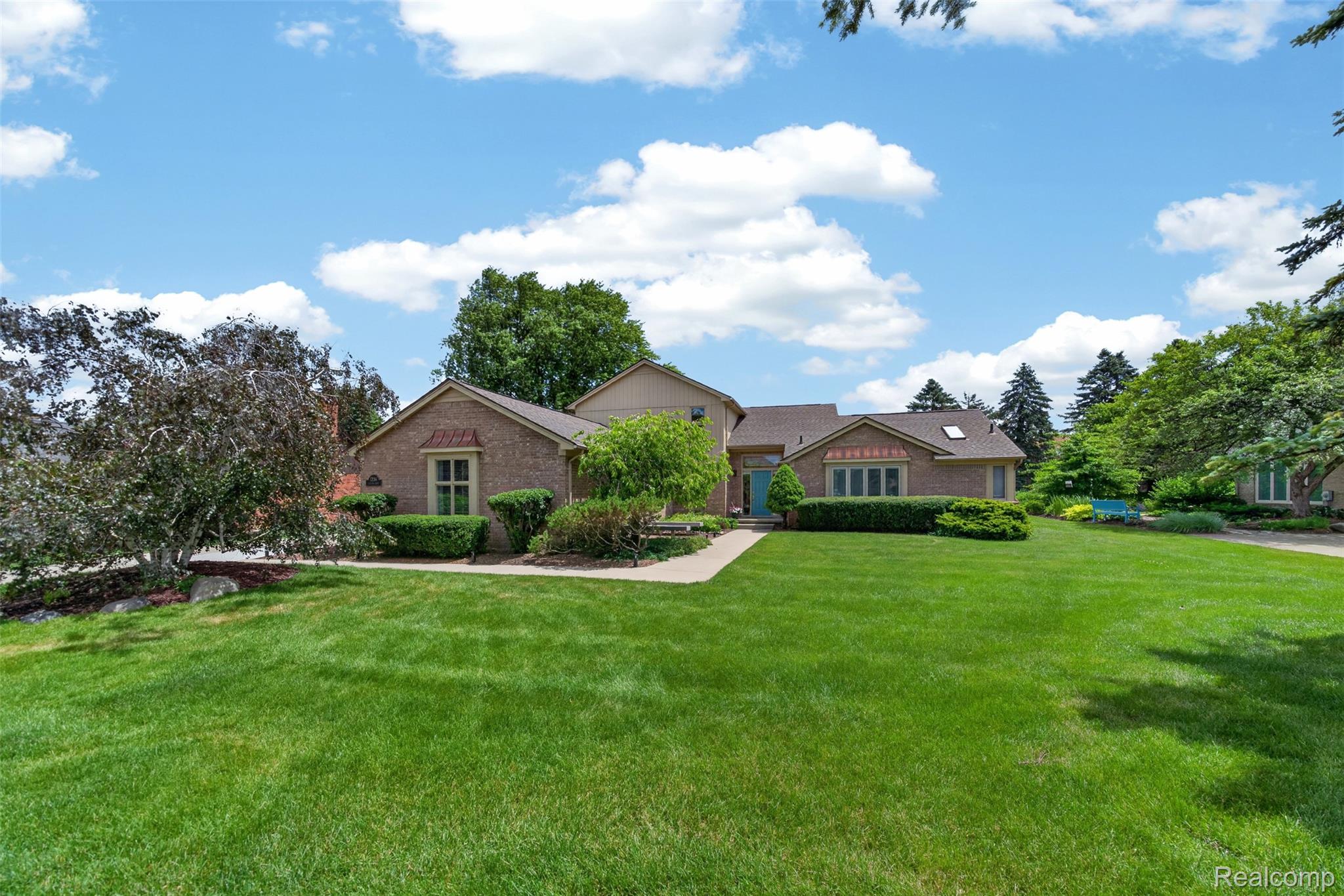 1236 Chaffer Drive Rochester, MI 48306 - Photo 3 of 76 Brick exterior residence featuring a prominent front lawn, mature trees, landscaped shrubbery, and a paved walkway