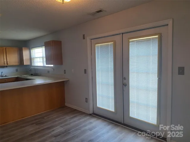 an empty room with wooden floor closet and windows