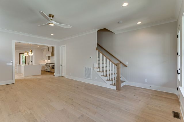 a view of an empty room with stairs and a ceiling fan
