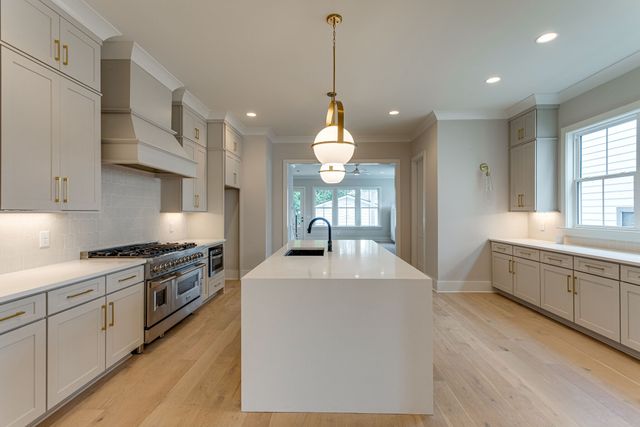 a large kitchen with granite countertop a sink a stove top oven a counter space and cabinets