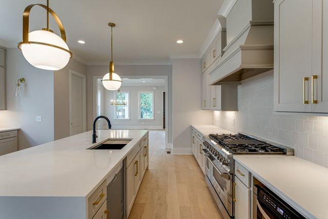 a kitchen with kitchen island stainless steel appliances a sink a stove and a wooden floors