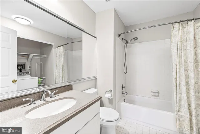 a bathroom with a granite countertop bathtub shower sink vanity mirror and toilet