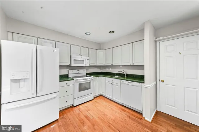 a kitchen with white cabinets and white appliances