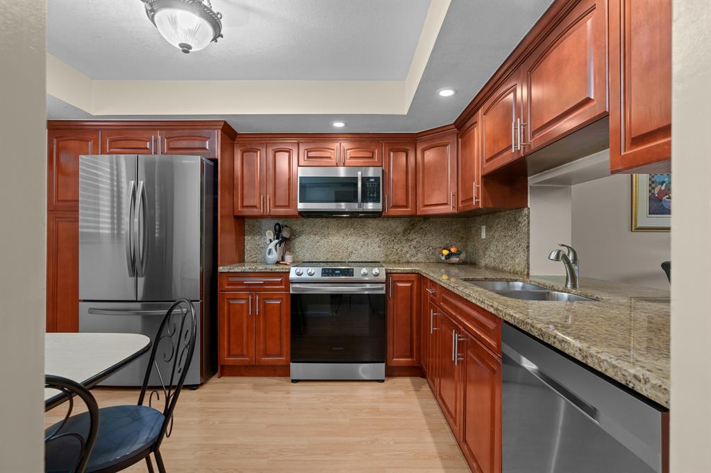 16051 Blatt Boulevard, Unit 212 Weston, FL 33326 - Photo 15 of 52 a kitchen with stainless steel appliances granite countertop a refrigerator a sink a stove and island