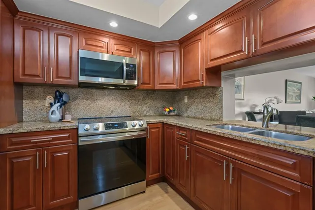 a kitchen with granite countertop a dining table chairs stainless steel appliances and cabinets