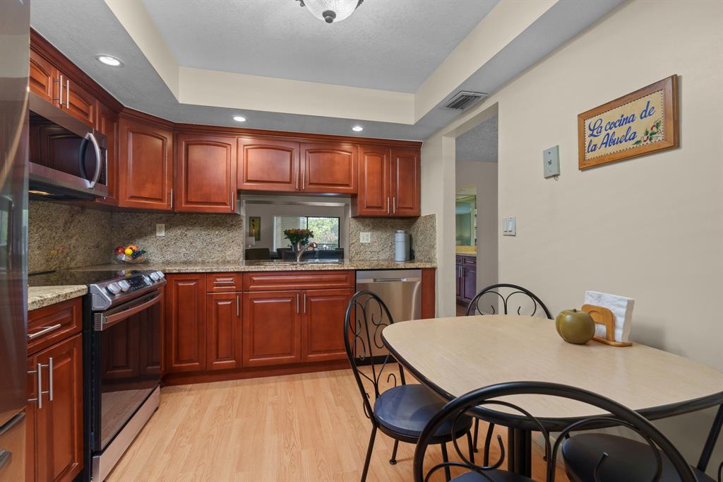 16051 Blatt Boulevard, Unit 212 Weston, FL 33326 - Photo 17 of 52 a kitchen with granite countertop a dining table chairs stainless steel appliances and cabinets