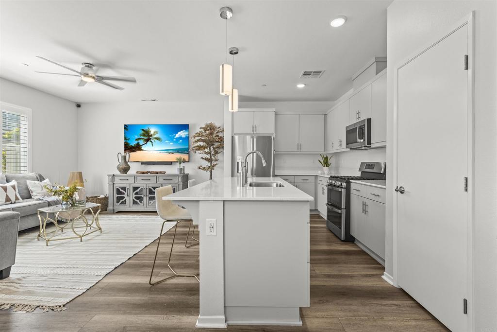 323 Citrine Trail Fallbrook, CA 92028 - Photo 3 of 21 a kitchen with stainless steel appliances kitchen island granite countertop a stove top oven a sink dishwasher a dining table and chairs with wooden floor