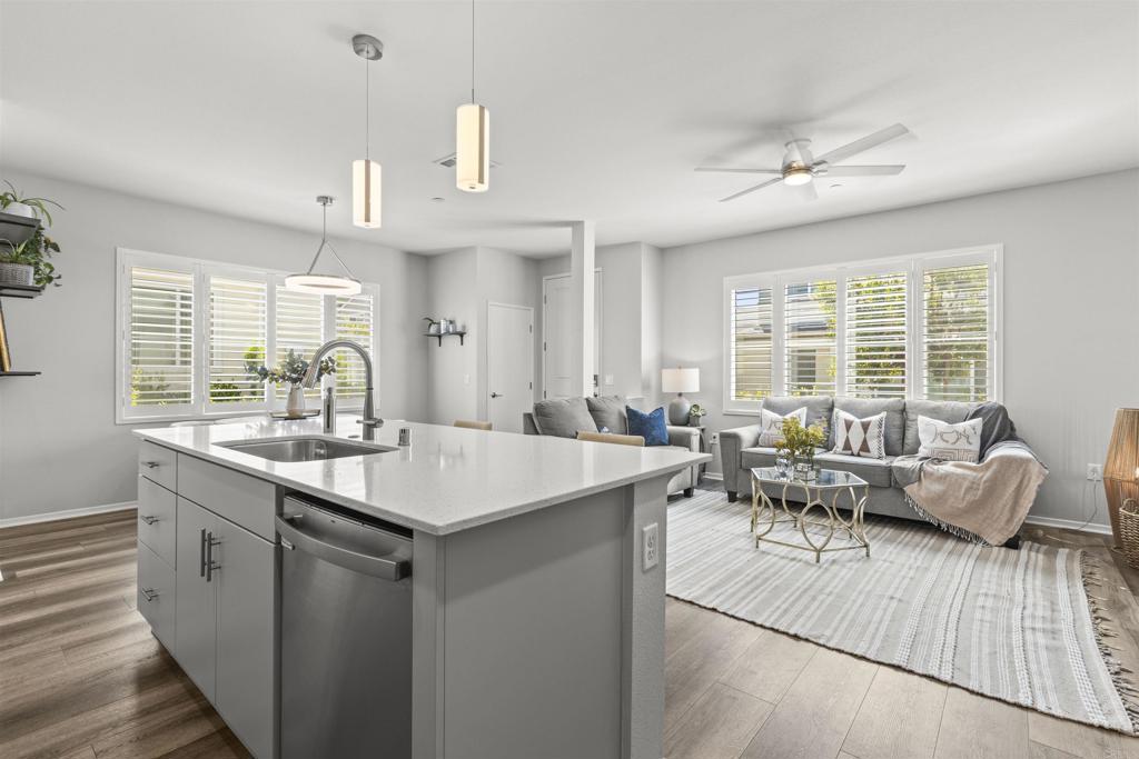 323 Citrine Trail Fallbrook, CA 92028 - Photo 10 of 21 a kitchen with granite countertop a sink dishwasher a stove and a dining table with wooden floor
