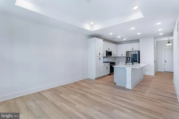 a view of kitchen with granite countertop refrigerator oven sink and white cabinets with wooden floor