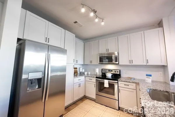 a kitchen with granite countertop white cabinets and stainless steel appliances