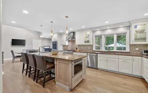 a kitchen with stainless steel appliances granite countertop a stove top oven a sink dishwasher a dining table and chairs with wooden floor