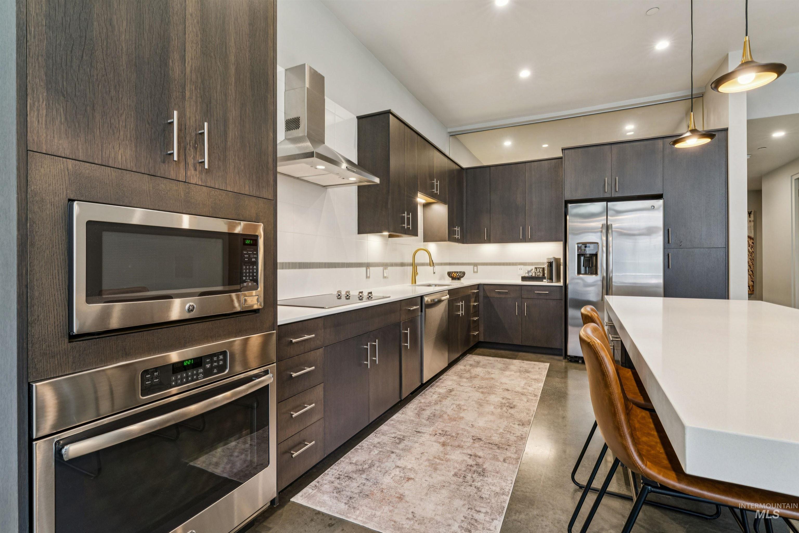 119 South 10th Street, Unit 307 Boise, ID 83702 - Photo 17 of 47 Kitchen featuring dark wood-finish cabinetry, stainless steel appliances, white countertops, and a full-height white subway tile backsplash