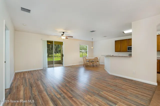 a view of an empty room with window and wooden floor