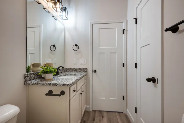 a bathroom with a granite countertop sink a toilet and shower