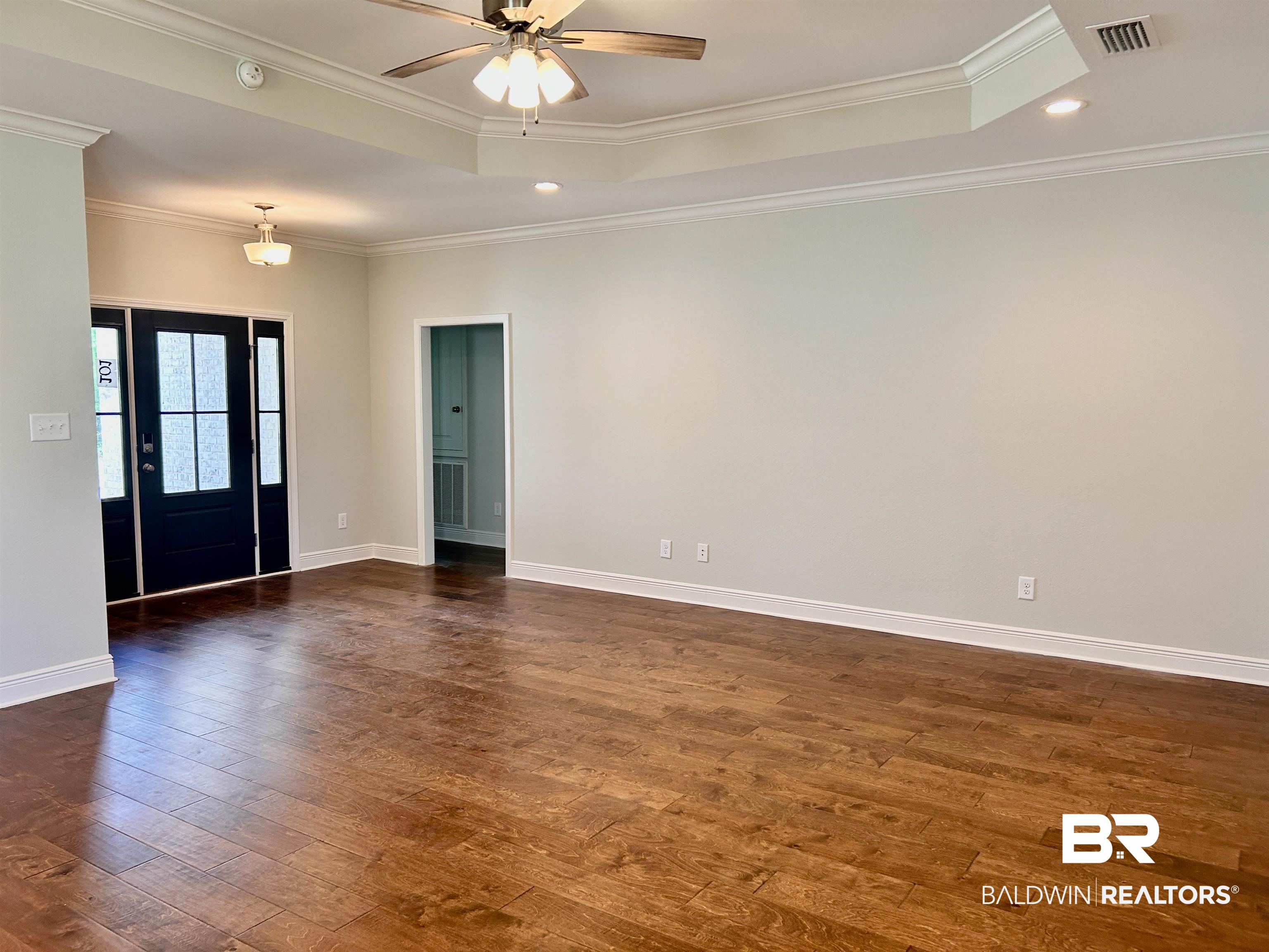 1267 Pembroke Way Foley, AL 36535 - Photo 3 of 17 Spare room featuring crown molding, dark wood-type flooring, ceiling fan, and a tray ceiling